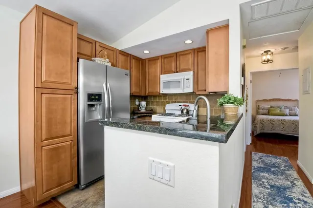 a kitchen with stainless steel appliances granite countertop a refrigerator a sink and a stove