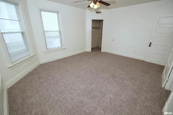 an empty room with windows and chandelier fan