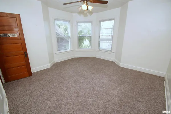 an empty room with windows and fan