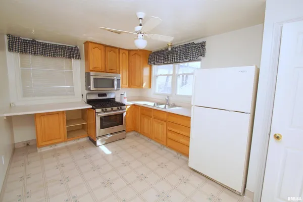 a kitchen with a refrigerator a stove a sink a counter space and cabinets