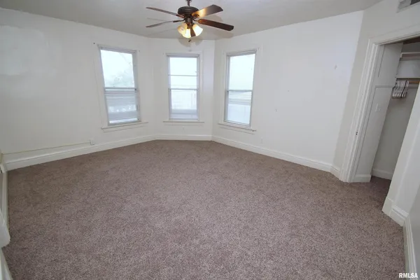 an empty room with windows and fan