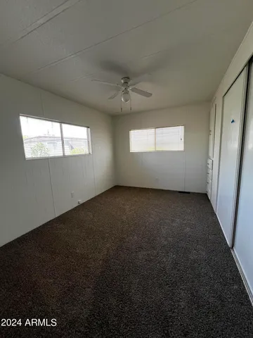 an empty room with windows and fan