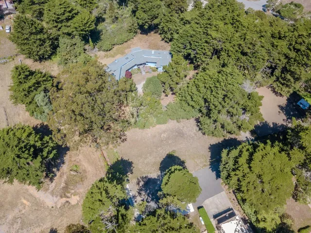 an aerial view of residential house with outdoor space and trees all around