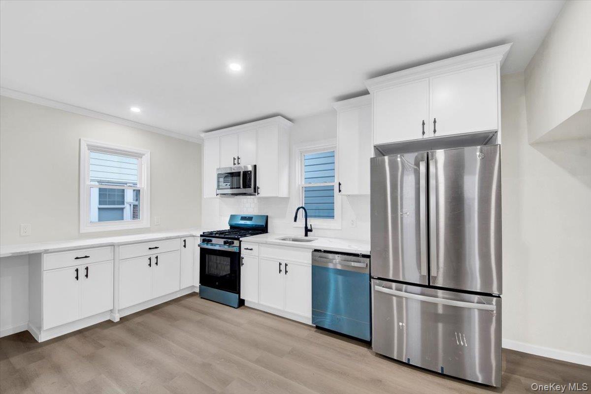 1625 Overing Street Bronx, NY 10461 - Photo 5 of 25 a kitchen with white cabinets stainless steel appliances and window