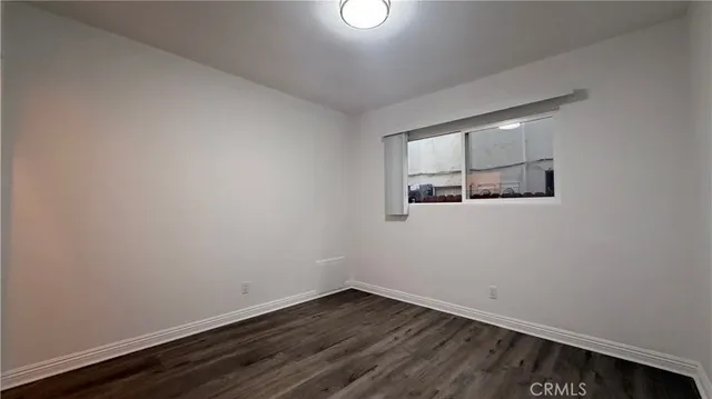 an empty room with wooden floor and window