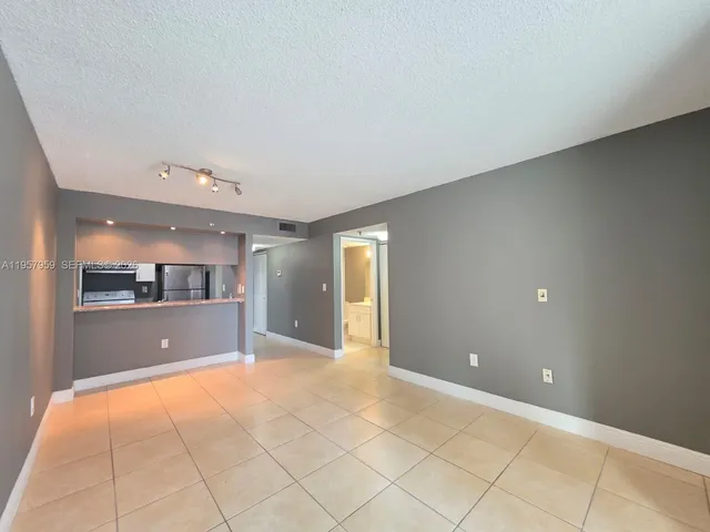 a view of an empty room with window and chandelier fan
