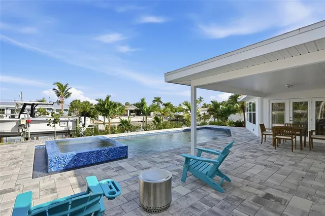 a view of swimming pool with seating space and trees in the background