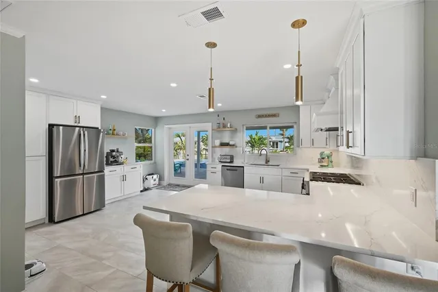 a kitchen with stainless steel appliances a refrigerator a sink a stove and white cabinets