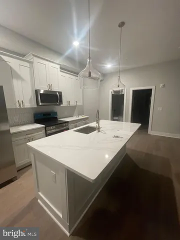 a kitchen with a sink a stove a refrigerator and white cabinets
