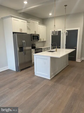 a large kitchen with stainless steel appliances a refrigerator a sink a stove a microwave a counter top space and cabinets