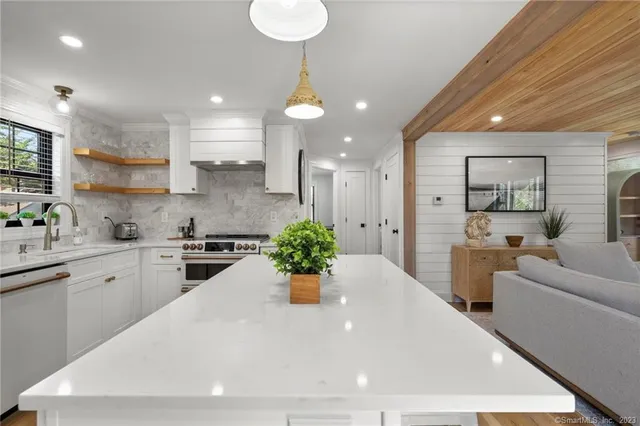a large white kitchen with a large window a sink and kitchen island