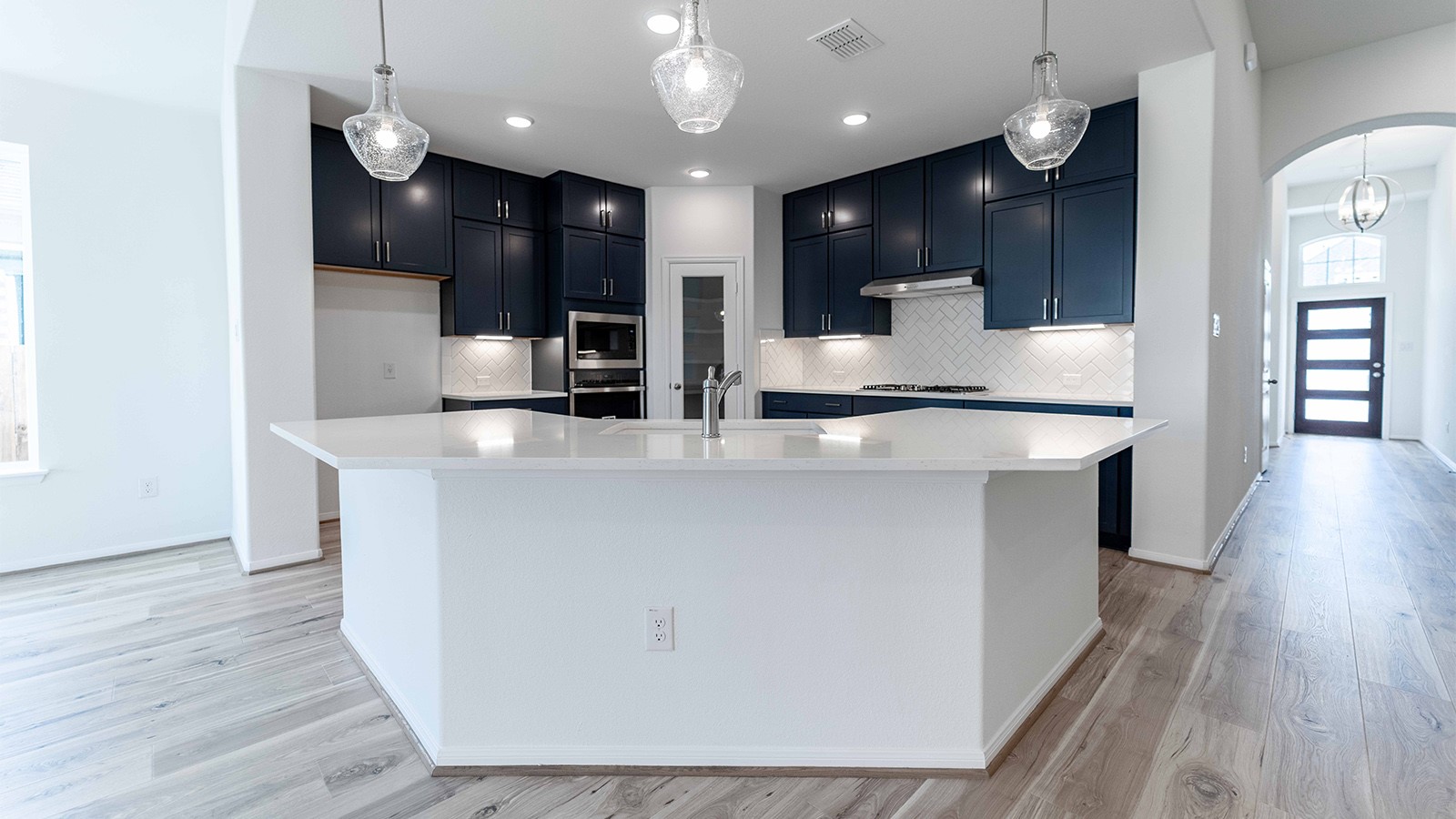 294 Rubber Tree Way Buda, TX 78610 - Photo 6 of 19 Kitchen featuring arched walkways, decorative light fixtures, a large island, stainless steel appliances, and decorative backsplash