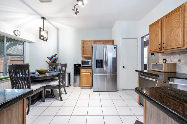 a kitchen with granite countertop a refrigerator and a stove top oven