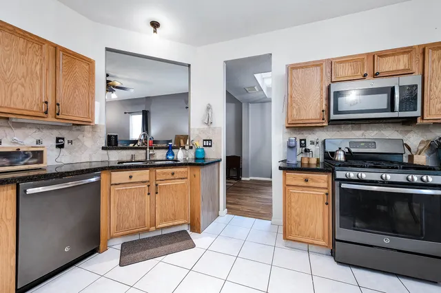 a kitchen with stainless steel appliances granite countertop a stove a sink and a microwave