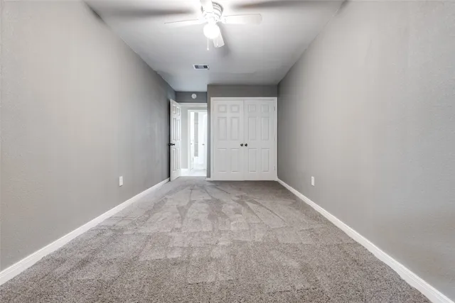 an empty room with a chandelier fan and windows
