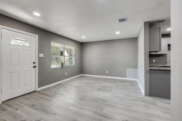 a view of an empty room with window and wooden floor