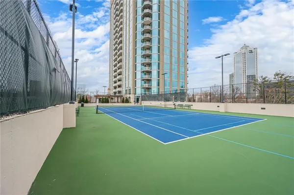 a living room with furniture two large window and wooden floor