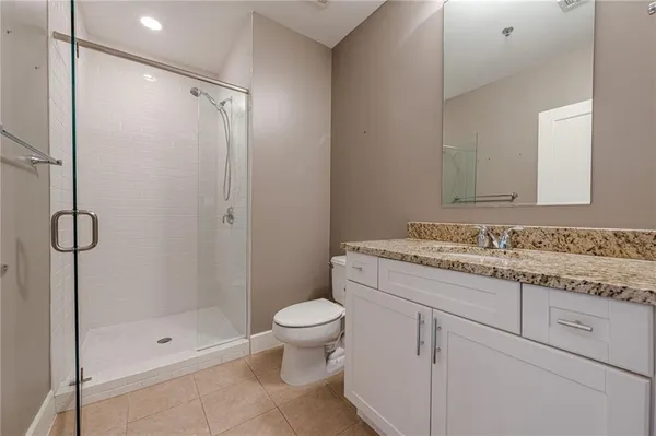 a bathroom with a granite countertop sink a toilet and shower