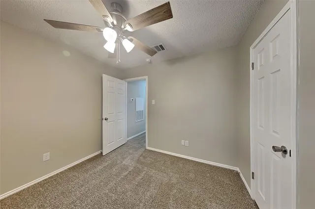 a view of an empty room and chandelier fan