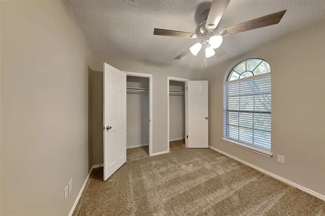 an empty room with windows and ceiling fan