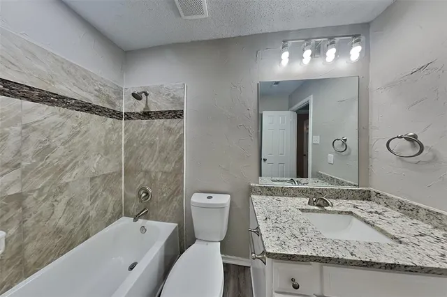 a bathroom with a granite countertop sink mirror toilet and bathtub