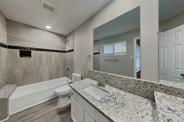 a bathroom with a granite countertop sink a toilet and bathtub