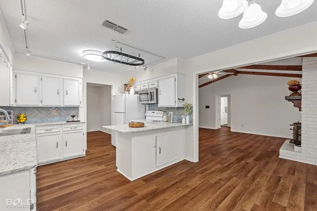 a kitchen with stainless steel appliances granite countertop a sink cabinets and wooden floor