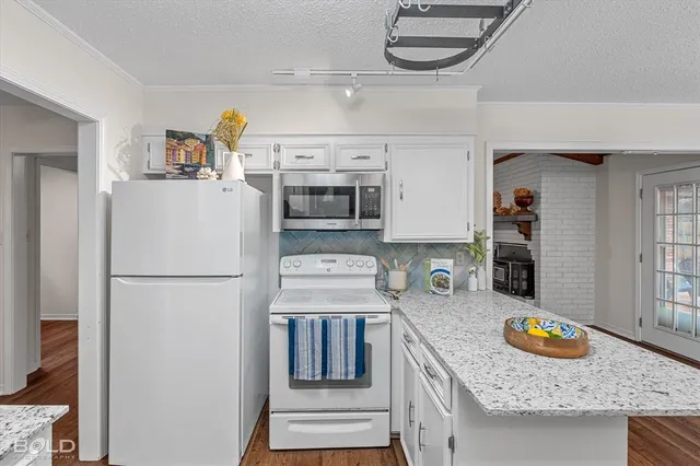 a kitchen with granite countertop a sink a stove and cabinets