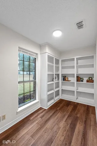 an empty room with wooden floor and windows