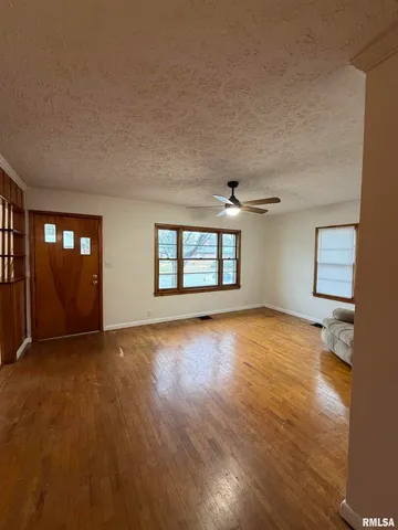 a view of an empty room with window and wooden floor