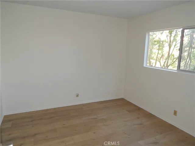 a view of empty room with wooden floor and windows