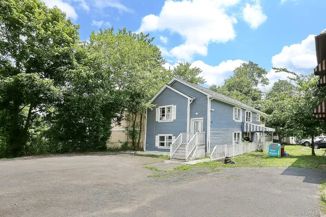 a view of a house with a yard and large trees