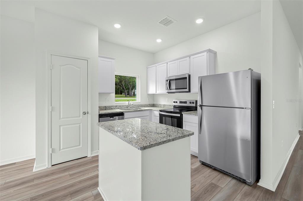 13283 Tula Loop Astatula, FL 34705 - Photo 3 of 19 a kitchen with a refrigerator a microwave oven a sink and dishwasher with wooden floor