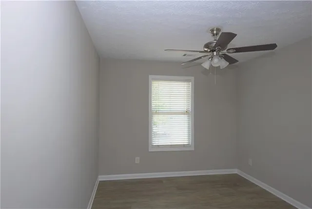 an empty room with a window and a fan
