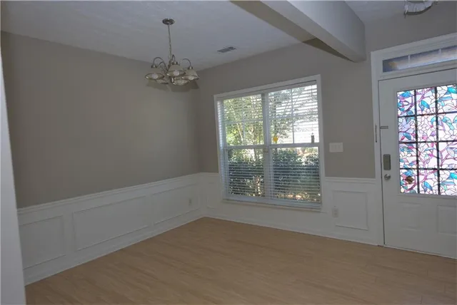 an empty room with chandelier fan and windows