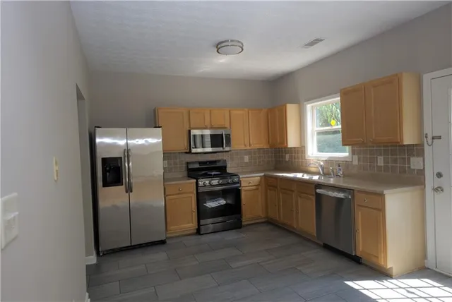a kitchen with stainless steel appliances granite countertop a refrigerator and a sink