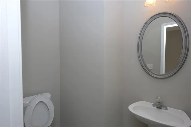a bathroom with a toilet mirror and sink
