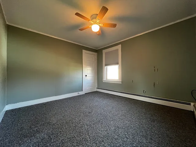 an empty room with a chandelier fan and windows