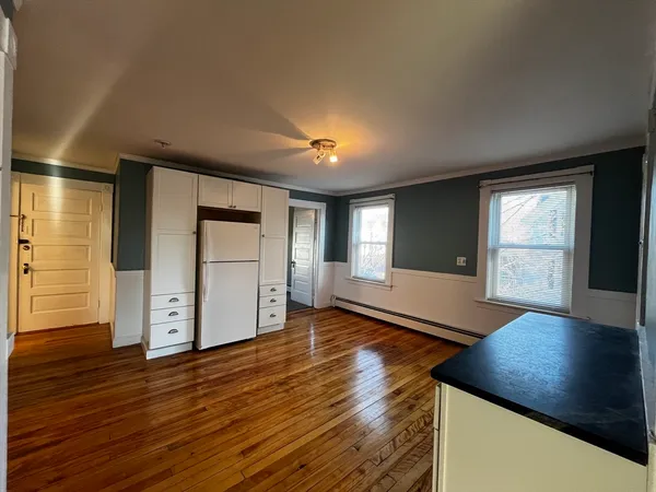 a view of an empty room with window and wooden floor