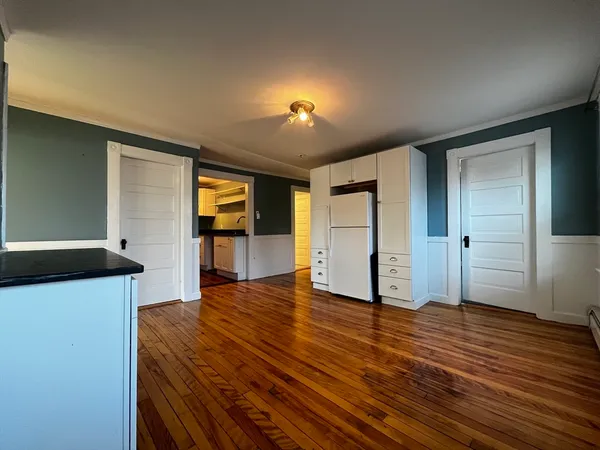 a view of a kitchen with wooden floor and a refrigerator