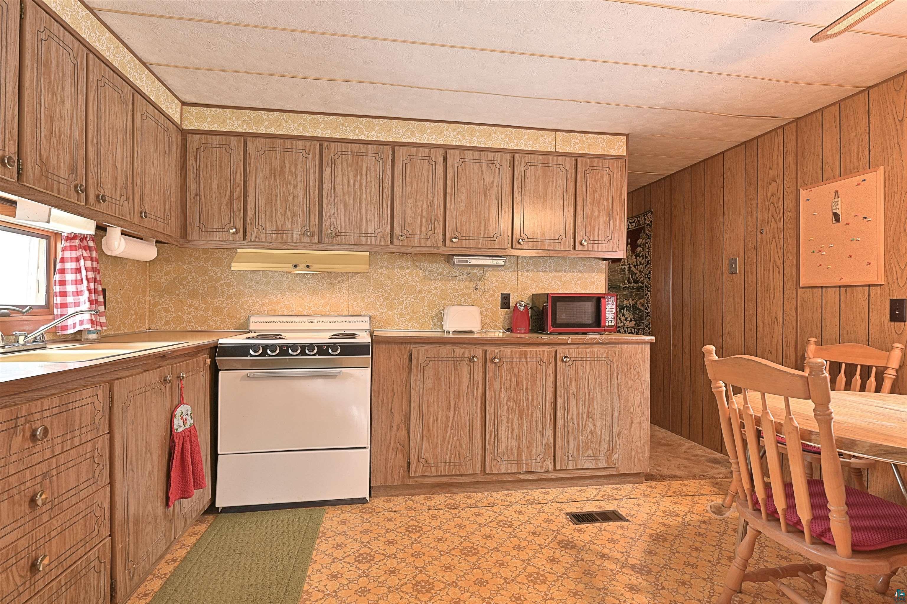 6800 Salveson Road Finland, MN 55603 - Photo 9 of 20 Kitchen featuring white electric range, wood finish cabinets, light countertops, wooden walls, and light floors