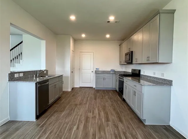 a large kitchen with stainless steel appliances granite countertop a stove a sink and a refrigerator