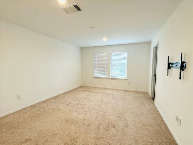 an empty room with windows and refrigerator