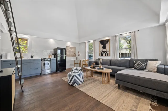 a living room with furniture kitchen view and a large window