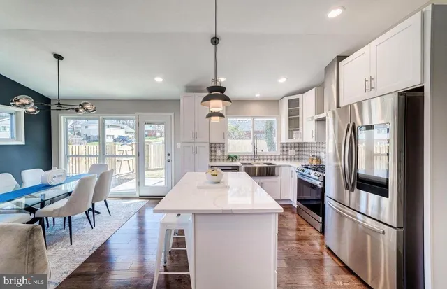 a kitchen with stainless steel appliances a dining table chairs stove refrigerator and cabinets