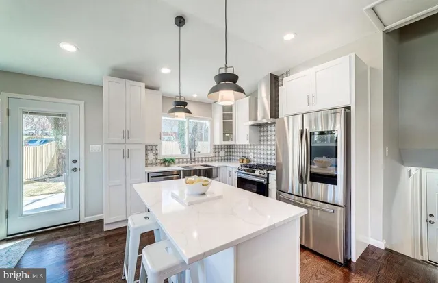 a kitchen with stainless steel appliances granite countertop a refrigerator a sink a stove a microwave a dining table and chairs with wooden floor