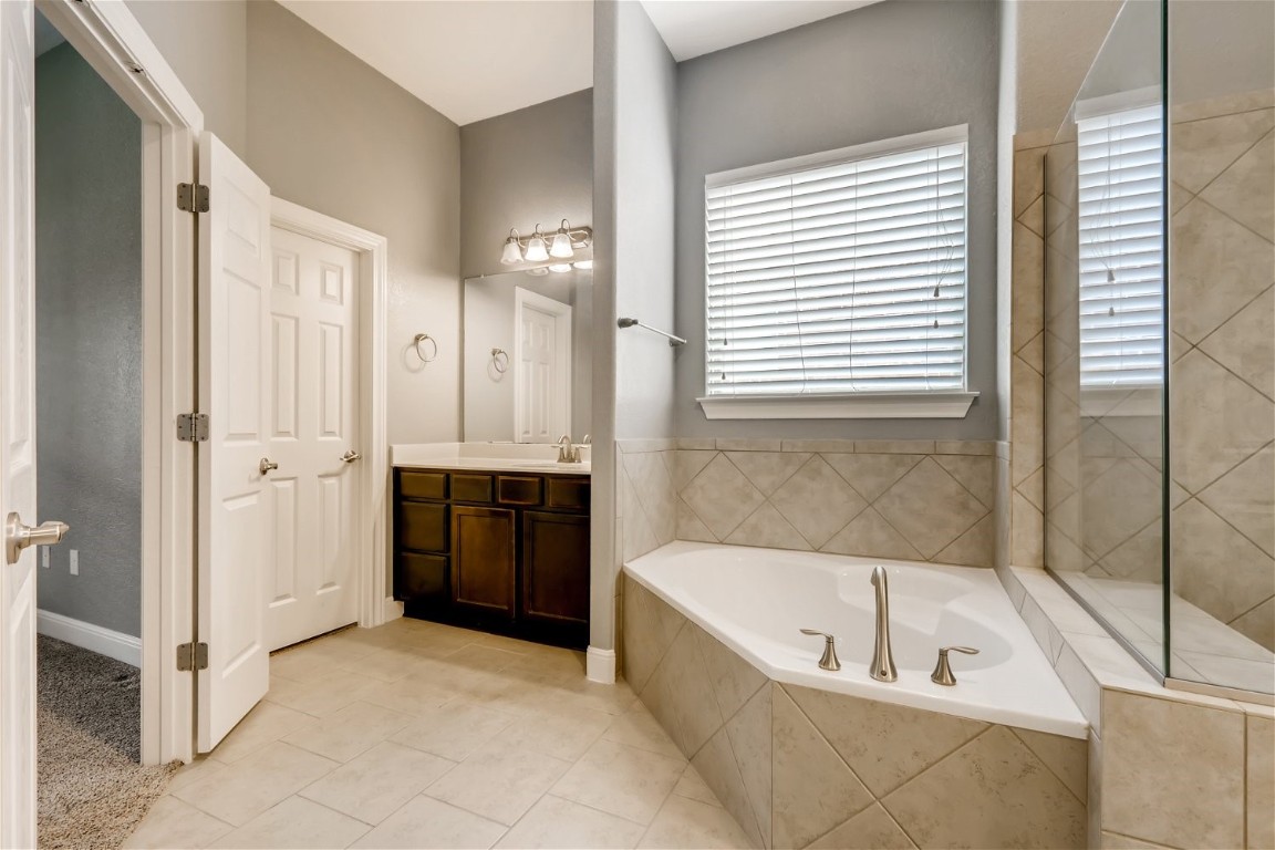 6108 Sabino Drive Spicewood, TX 78669 - Photo 14 of 22 a bathroom with a tub shower and windows