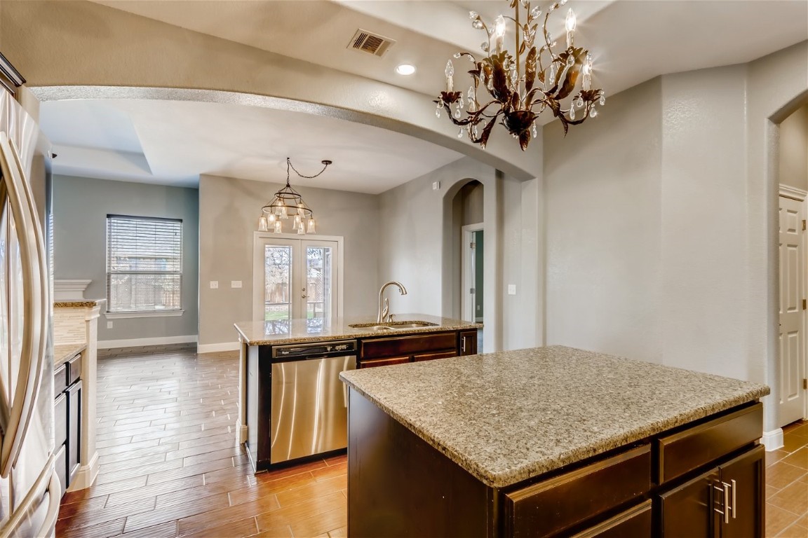6108 Sabino Drive Spicewood, TX 78669 - Photo 5 of 22 a view of a kitchen island a sink wooden floor and a chandelier