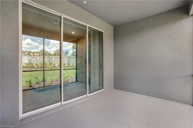 a view of an empty room and window with kitchen view