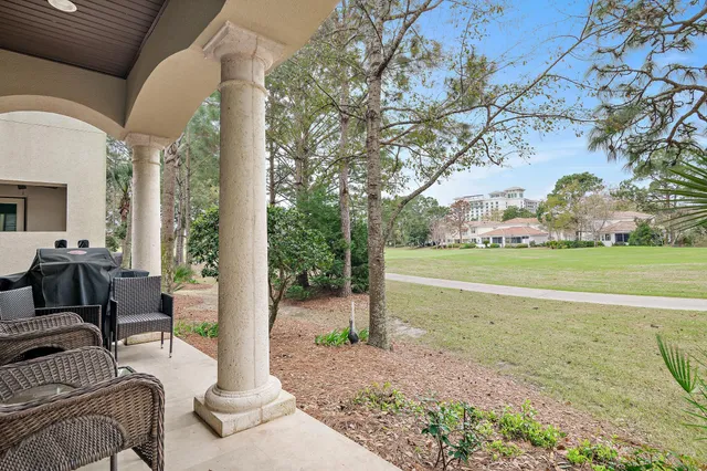 a view of a patio with couches plants and large trees